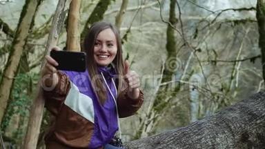 一个在紫色<strong>奥林匹亚</strong>的快乐女孩在长满青苔的树木的背景下展示自己，并制作自拍